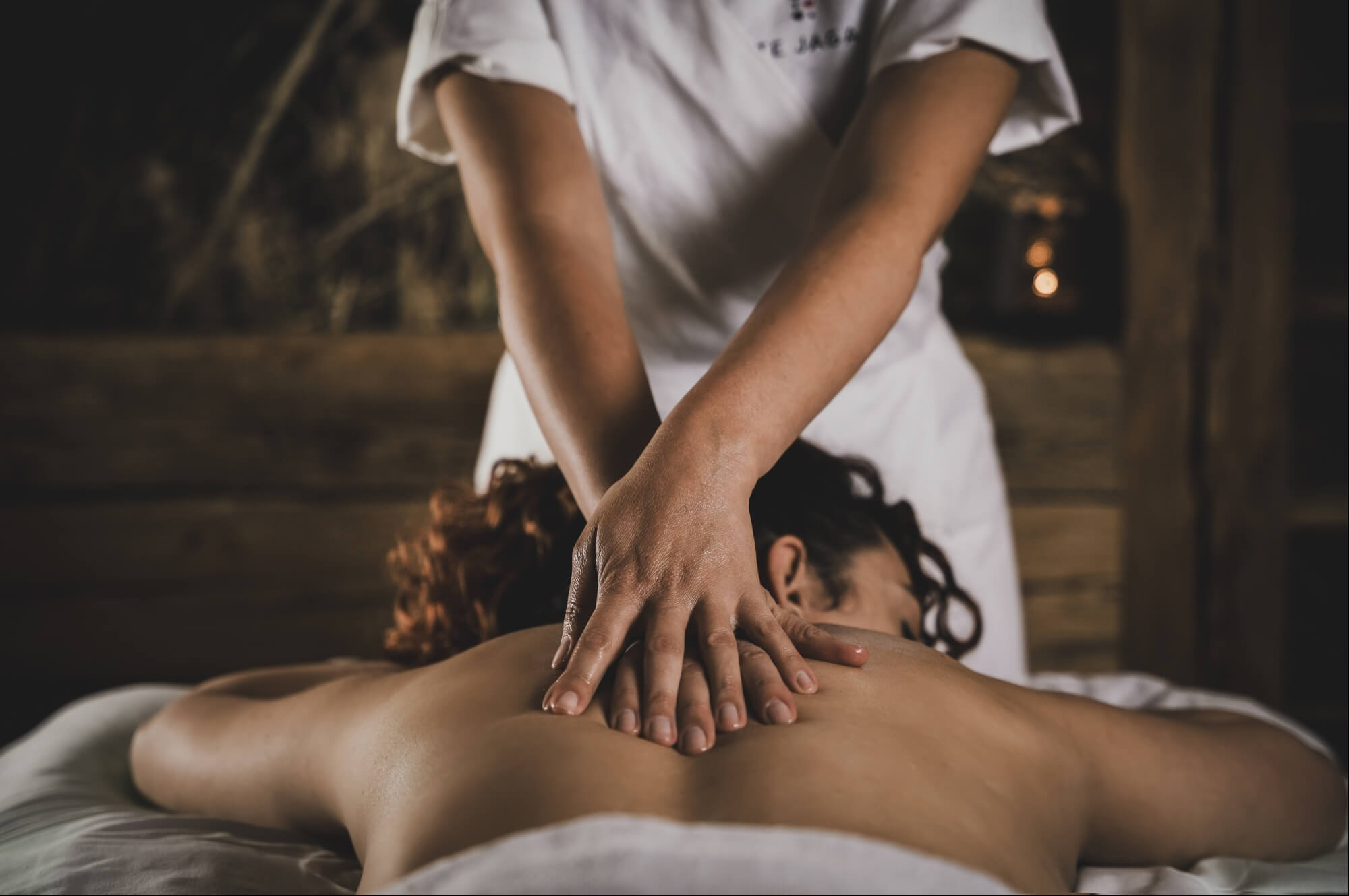 Una donna riceve un massaggio da un'altra donna in un ambiente sereno e luminoso.