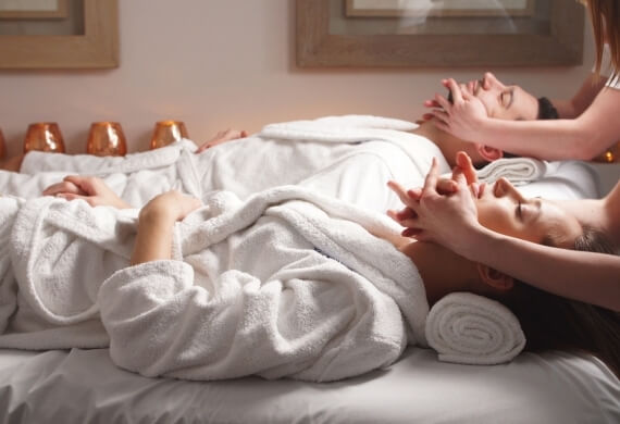 Due persone ricevono massaggi facciali in una spa.