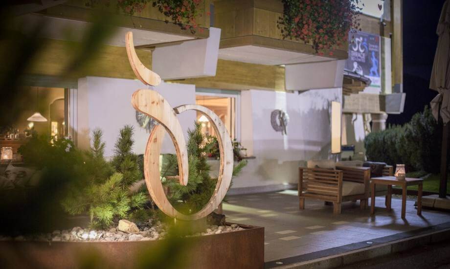 Scultura in legno a forma di 60, edificio con veranda e mobili da esterno come sedie e tavoli.