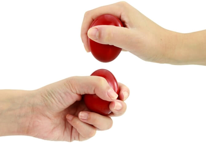 Le mani di una persona tengono due oggetti rossi a forma di uovo su uno sfondo bianco.