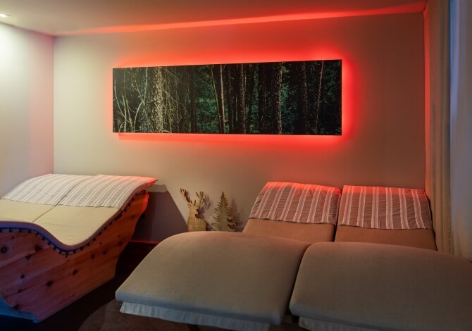 Una stanza con un dipinto a tema forestale, due letti, un baule di legno e un'atmosfera accogliente.