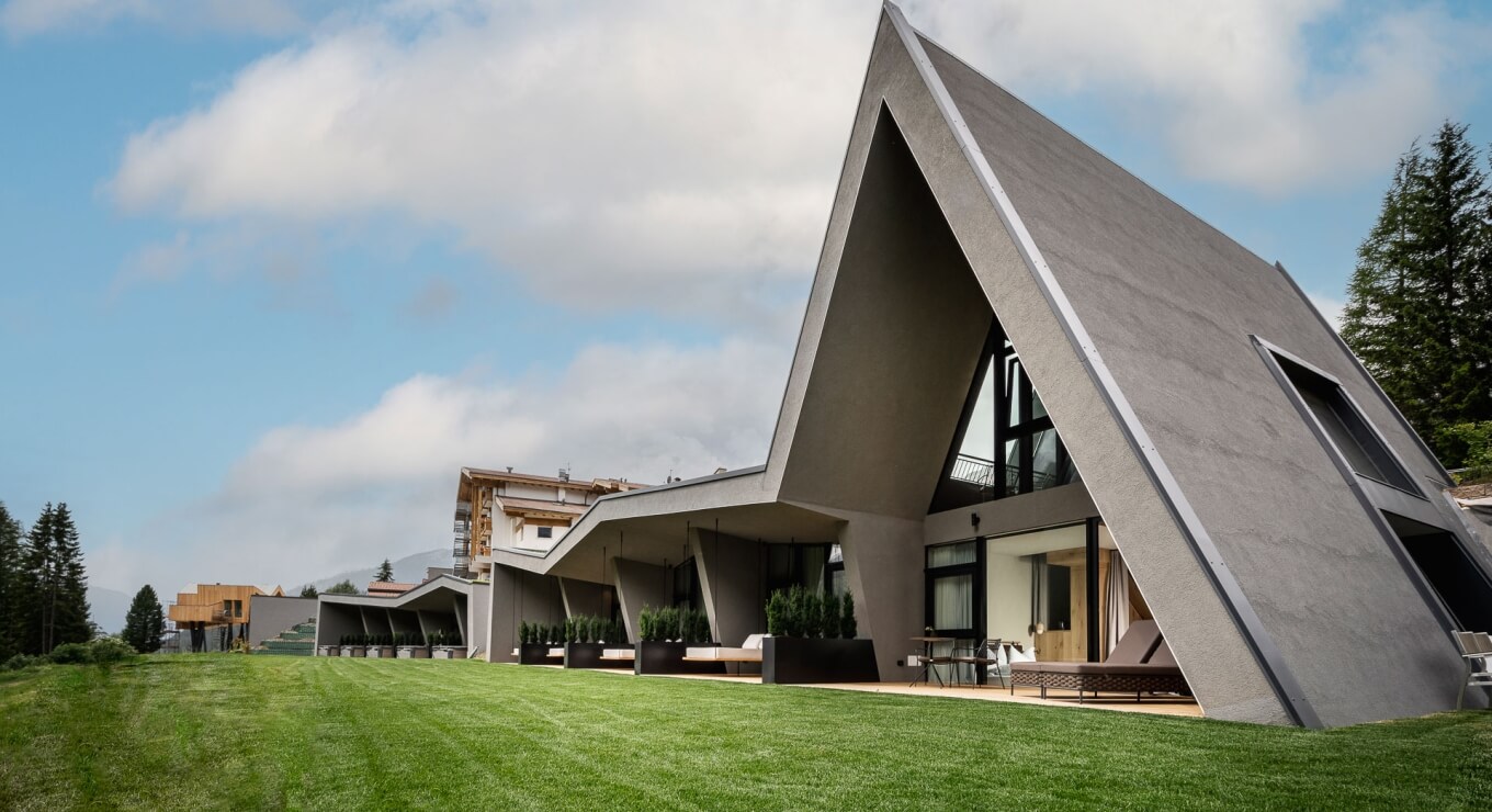 Edificio moderno con tetto appuntito, finestre grandi e prato verde.