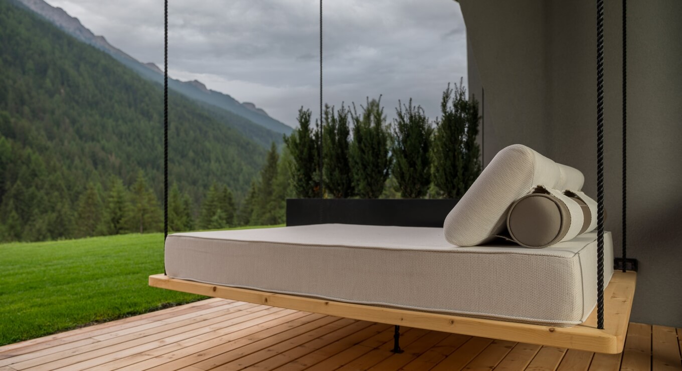 Letto sospeso su un deck, circondato da alberi e montagne.