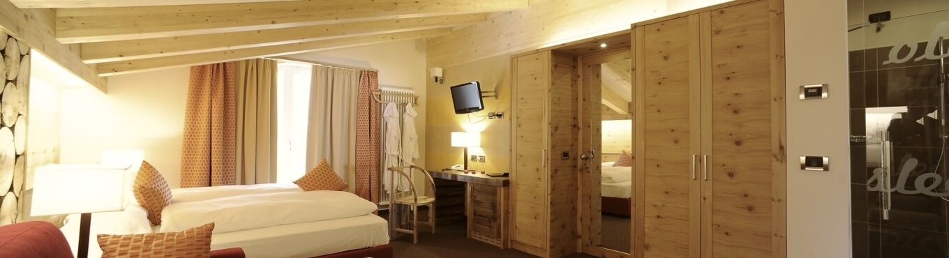 Camera d'hotel con due letti, armadi in legno e doccia.
