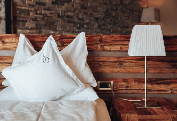 Camera da letto serena con letto bianco, comodino e lampada, parete in legno che crea un'atmosfera tranquilla.