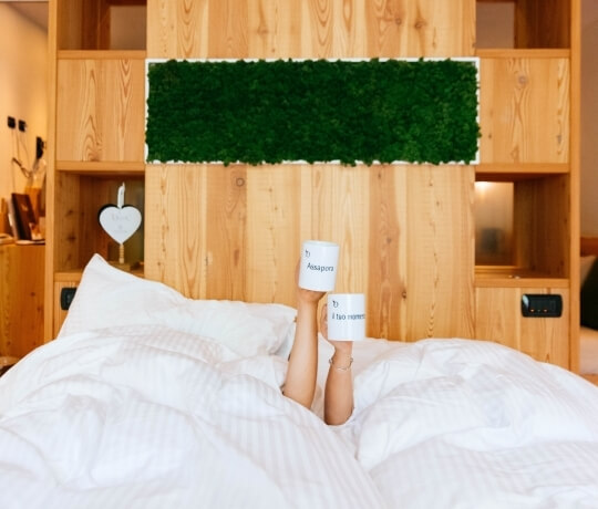 Letto con lenzuola bianche e tazze bianche sotto le coperte.