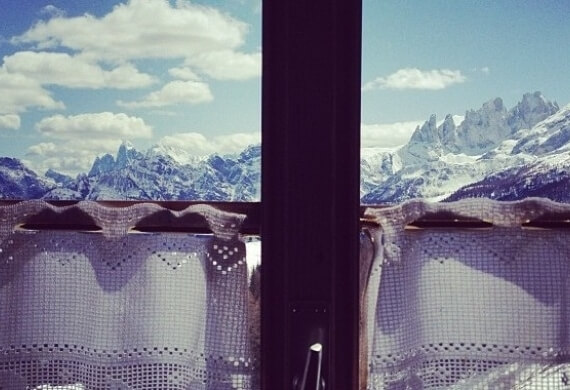 Due fotografie di montagne innevate: una con un lenzuolo che oscura la vista, l'altra senza ostacoli, su sfondo ciano.