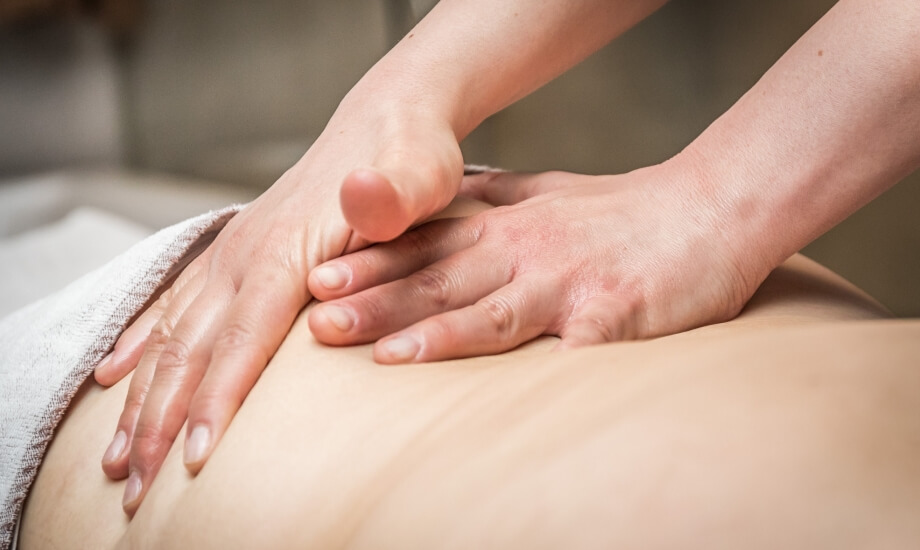 Sessione di massaggio con le mani del terapista che applicano pressione sulla schiena del cliente, in un ambiente professionale.