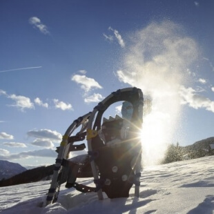 Scena innevata con un oggetto meccanico in primo piano, montagne sullo sfondo e cielo blu con nuvole bianche.