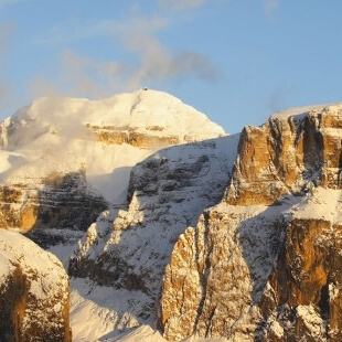 Catena montuosa coperta di neve sotto un cielo blu con nuvole, trasmettendo serenità e tranquillità.