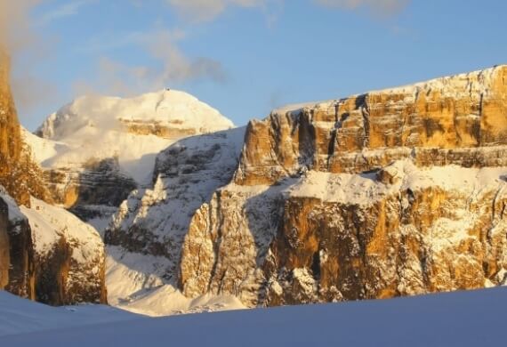 Paesaggio invernale sereno con montagne innevate sotto un cielo blu chiaro, trasmettendo tranquillità e bellezza naturale.