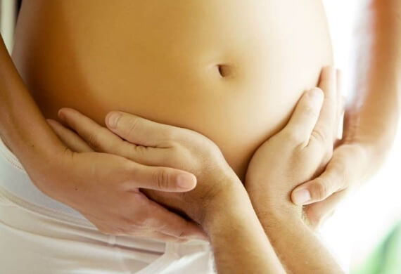 Due mani bianche poggiano su un addome nudo e liscio.