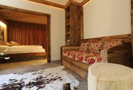 Una stanza accogliente con un divano rosso e bianco, tavolino in legno, tappeto scuro e pareti bianche.