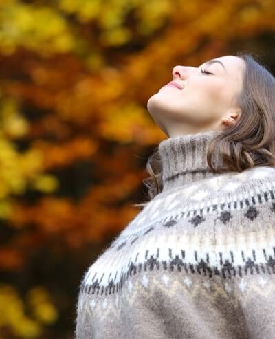 Donna con maglione a yoke, sfondo autunnale sfocato.