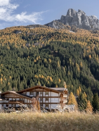 Edificio OLYMPIA ai piedi di una montagna autunnale.