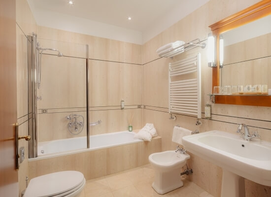 Bagno d'hotel con vasca, doccia, lavabo e bidet bianchi.