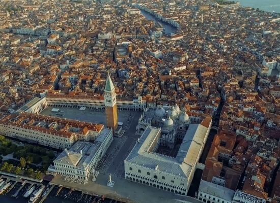 Vista aerea di Venezia con un grande edificio bianco e torre centrale, circondato da strutture di varie forme e dimensioni.