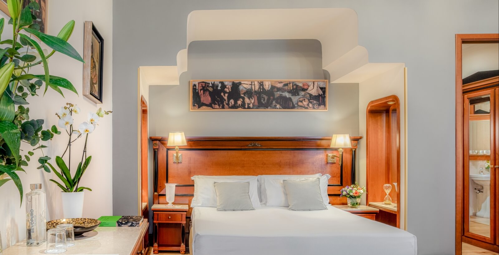 Camera da letto accogliente con letto matrimoniale, comodini, lampade, dipinto e accesso a un bagno privato.