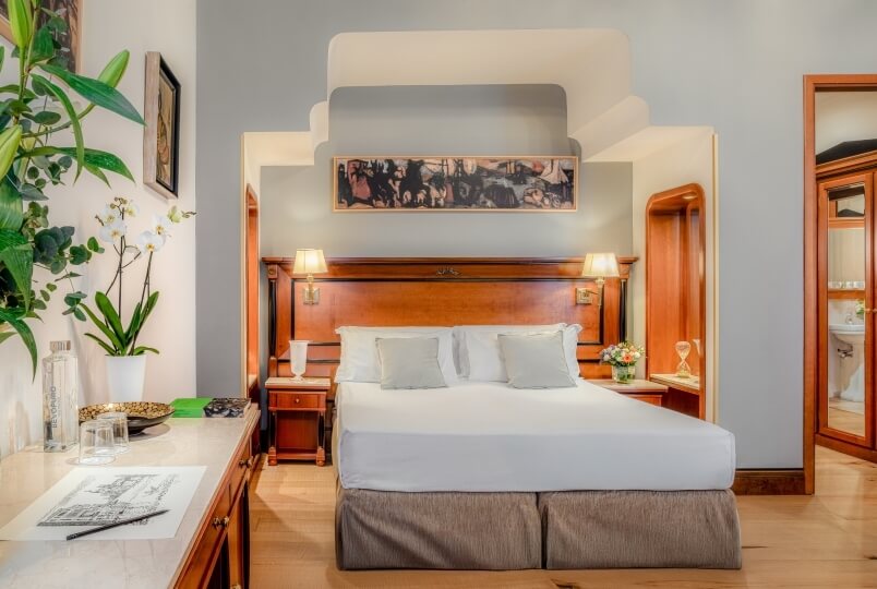 Camera serena con letto grande, testiera in legno scuro, lampade, cassettiera e decorazioni che creano un'atmosfera accogliente.