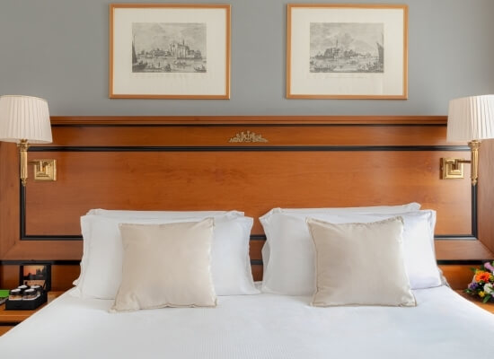 Serene bedroom featuring a bed with white sheets, beige throw pillows, wooden headboard, nightstands, and framed pictures.