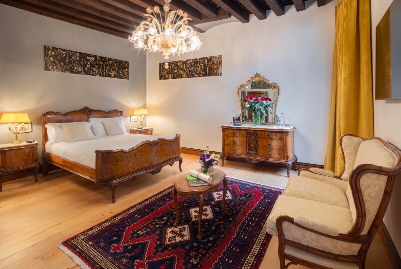 Camera accogliente in stile vintage con mobili eleganti, illuminata da un lampadario e lampade da tavolo, atmosfera rilassante.