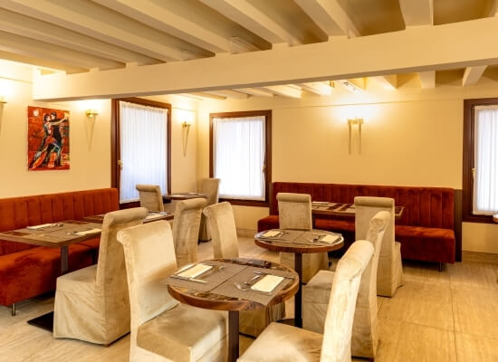 Ristorante vuoto con atmosfera accogliente, tavoli rotondi e sedie beige, pronto per il servizio.