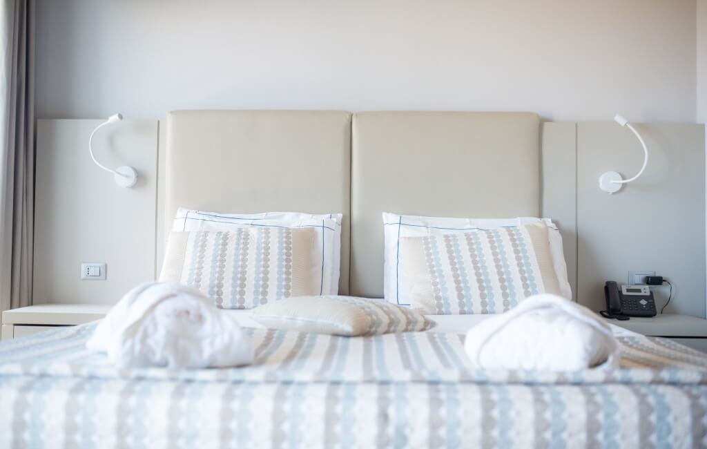 Ein einladendes Schlafzimmer mit einem Bett, weißen und blauen gestreiften Bettdecken, Nachttischen und sanfter Beleuchtung.