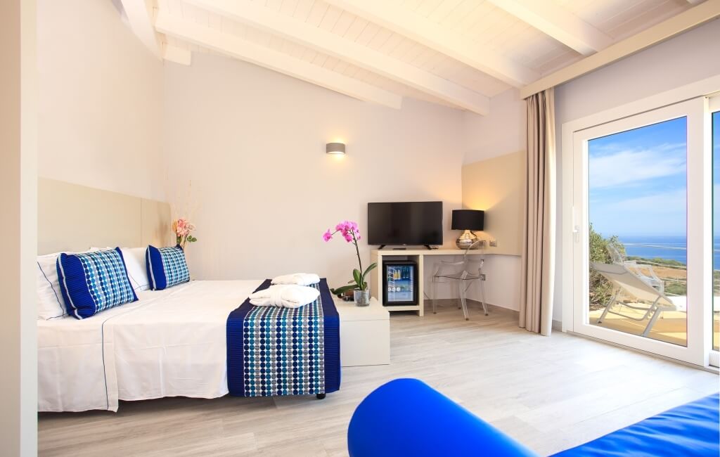 Ein modernes Hotelzimmer mit zwei Einzelbetten, minimalistischer Dekoration und Blick auf das Meer durch Schiebetüren.