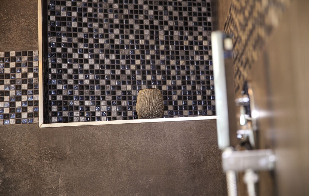 Modernes Badezimmer mit Dusche, silbernem Griff und dekorativer Wand aus schwarz-weißen Kacheln im Schachbrettmuster.