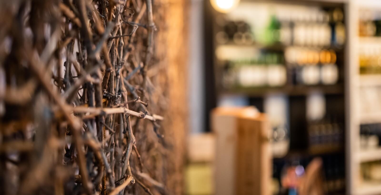 Gros plan sur un mur avec des branches entrelacées et des grappes de raisins, arrière-plan flou d'une cave à vin.