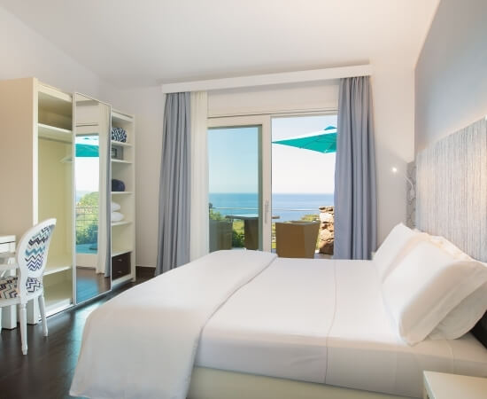 Camera d'hotel moderna e serena con vista sull'oceano, letto confortevole e arredi eleganti in un ambiente luminoso.
