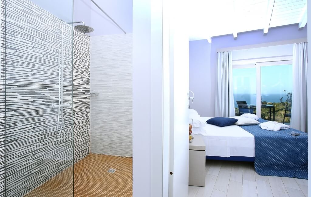 Modernes Badezimmer mit Dusche und Schlafzimmer, helles Design, Fenster mit Aussicht, ruhige Atmosphäre.