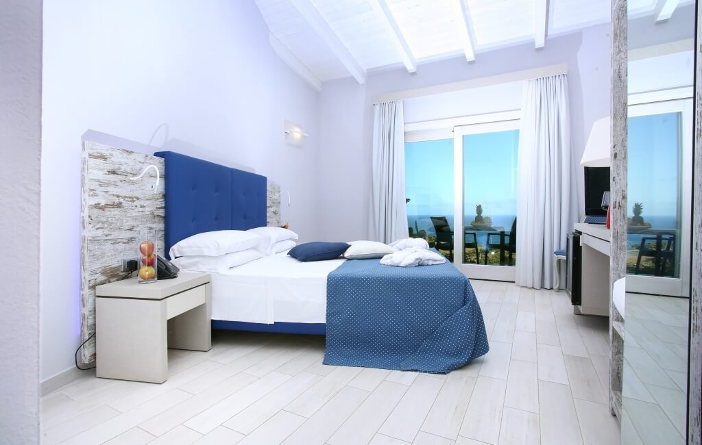 Ein einladendes Hotelzimmer mit Meerblick, minimalistischer Einrichtung und beruhigender Farbpalette in Weiß und Blau.