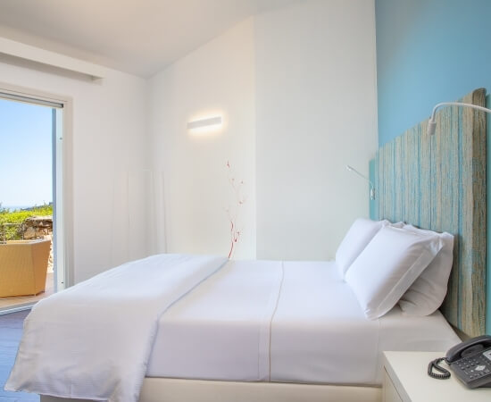 Camera serena con letto bianco, parete blu, finestra su patio e vasca da bagno in piastrelle blu-grigie.