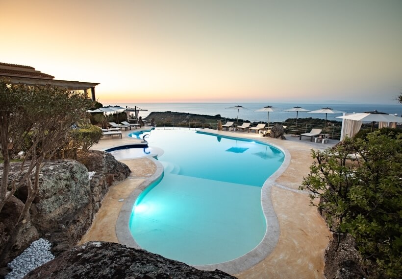 Luxuriöser Infinity-Pool mit Blick auf den Ozean, umgeben von Felsen und einem modernen, wellenförmigen Design.