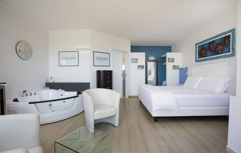 Modernes, minimalistisches Zimmer mit Bett, Badewanne und Kunstwerken in beruhigenden Farben, vermittelt eine entspannende Atmosphäre.