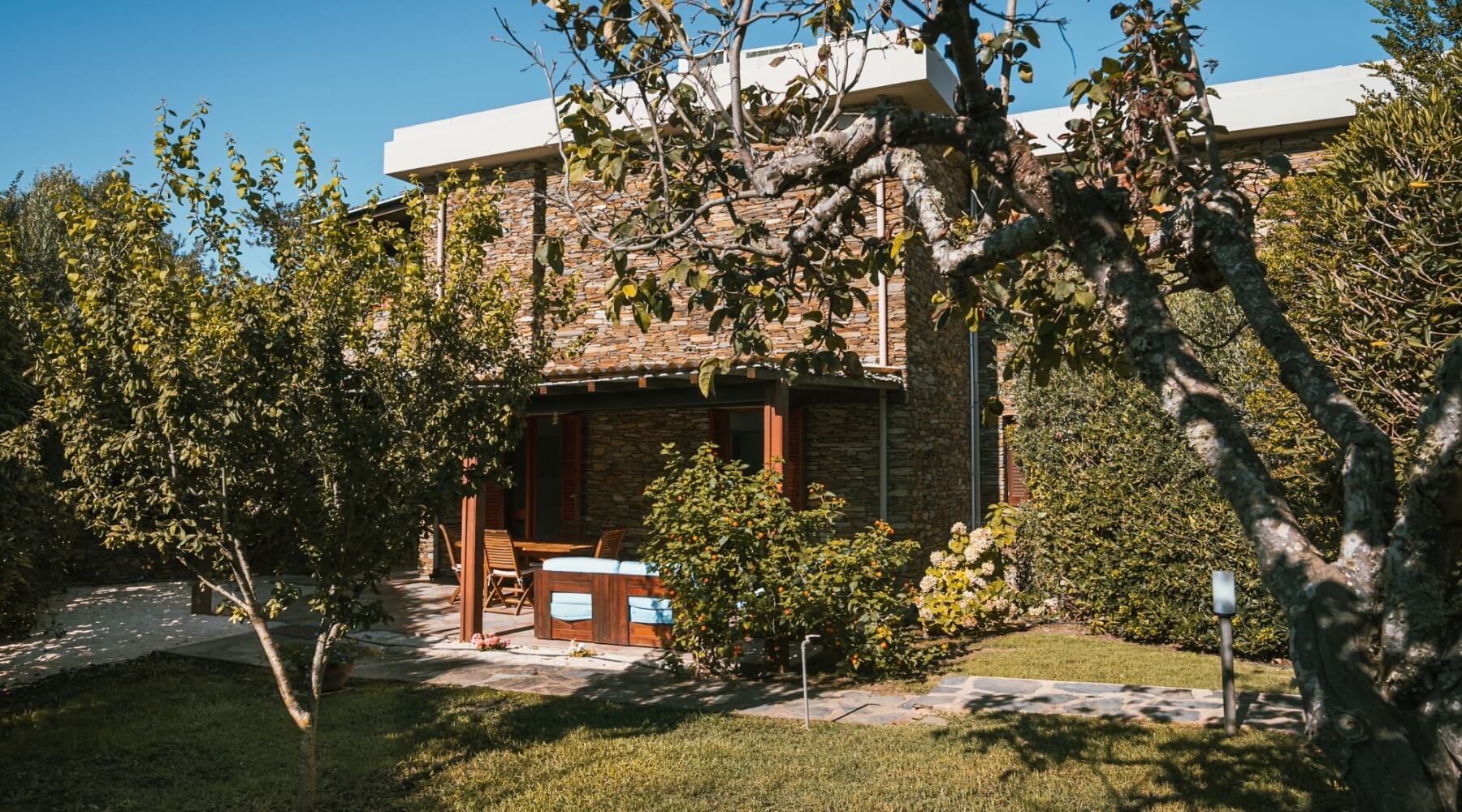 Patio con sedie e tavolo, edificio in pietra, cielo blu.
