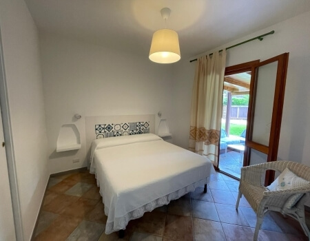 Camera d'hotel con letto, patio e sedia in vimini.