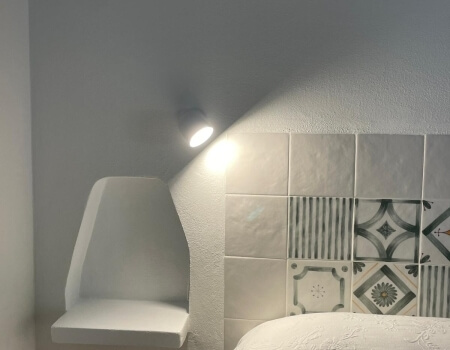 Illuminato testiera piastrellata con motivi geometrici e scaffale bianco.