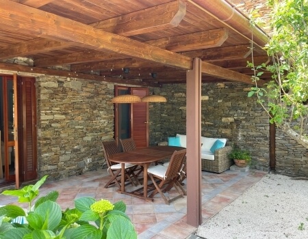 Area pranzo all'aperto con tavolo, sedie e divano in rattan.
