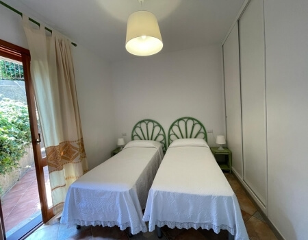Camera con due letti singoli, comodino verde e porta in vetro.