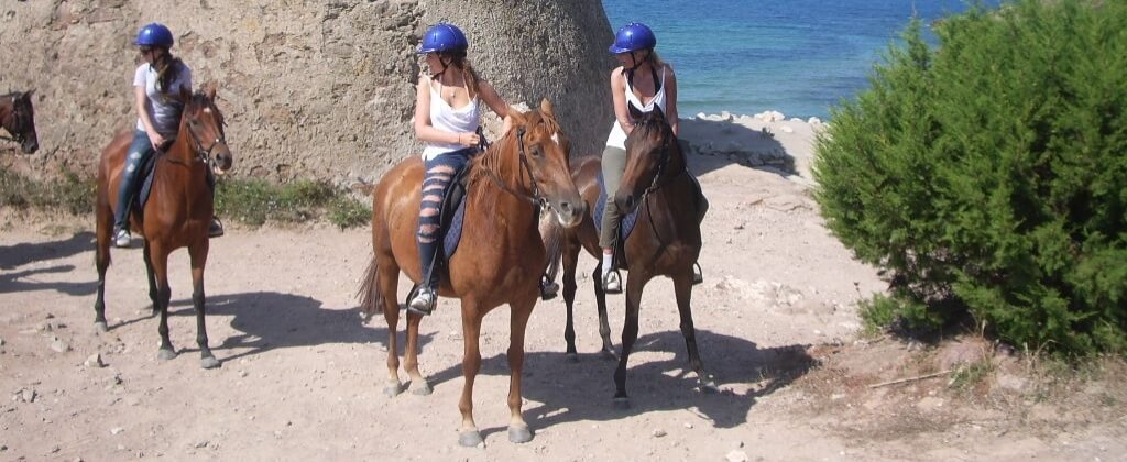 Persone a cavallo vicino a un corpo d'acqua, indossando caschi blu.