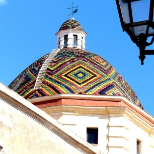 Edificio a cupola con tetto di piastrelle colorate e cielo blu.