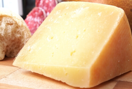 Wedge of cheese, bread, and sausages on a wooden surface.   Fetta di formaggio, pane e salsicce su una superficie di legno.