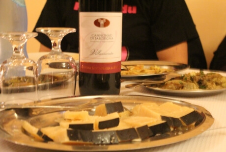 Una bottiglia di vino rosso con formaggi e bicchieri.