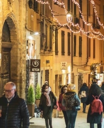Strada stretta con luci decorative e persone che camminano.