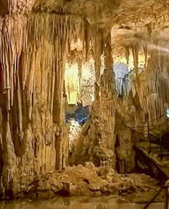 Interno di una grotta con stalattiti, stalagmiti e un sentiero.