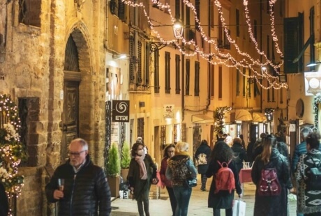 Scena notturna di strada con persone e luci decorative.