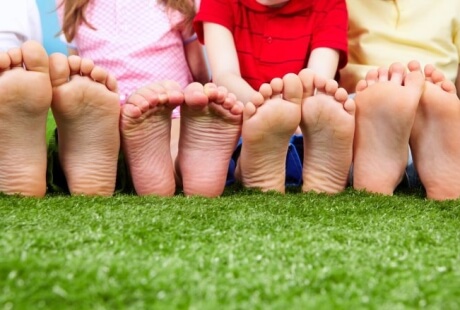 Piedi nudi di bambini su un prato artificiale verde brillante.