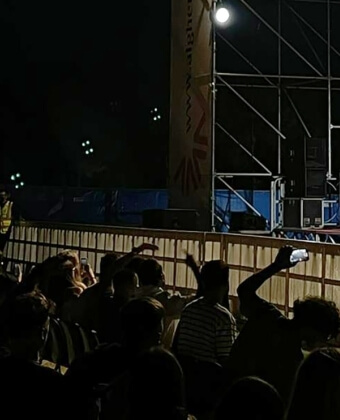 Folla davanti a un palco con banner "www.algher.it" e luci.